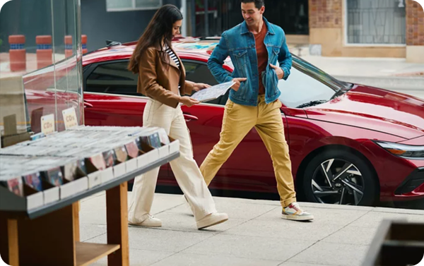 Hyundai Bluelink app on smartphone showing vehicle controls next to red Elantra