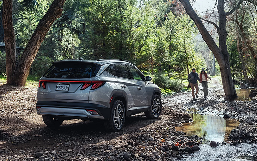 2026 Hyundai TUCSON Plug-in Hybrid rear view with couple in forest