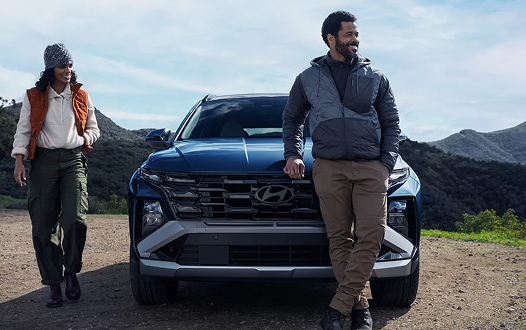 Couple walking towards 2026 Hyundai Tucson Hybrid in mountains