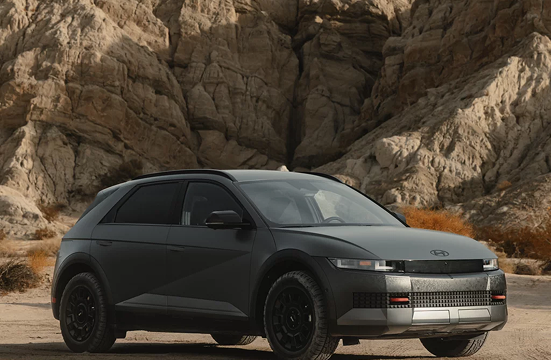 A matte black IONIQ 5 XRT parked on gravel beneath a rocky canyon wall