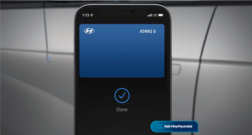 A smartphone held beside an IONIQ 5 door showing the Hyundai Digital Key unlock confirmation