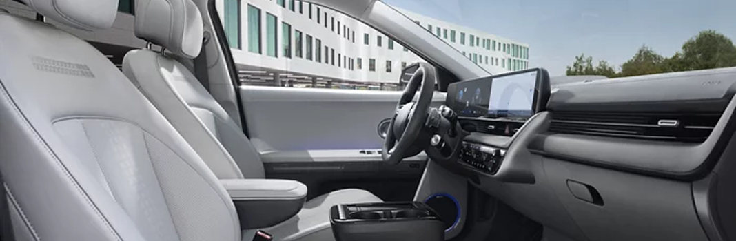 The light gray IONIQ 5 cabin seen from the back seat toward the touchscreen