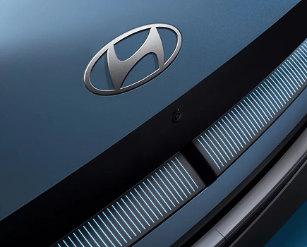 Close-up of the Hyundai badge above the pixel grille of a blue IONIQ 5