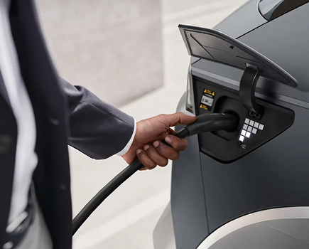 A hand plugging a charging connector into the charge port of a gray IONIQ 5