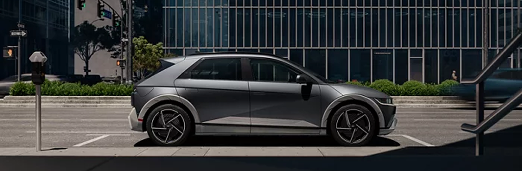 A silver IONIQ 5 parked in profile along a city street