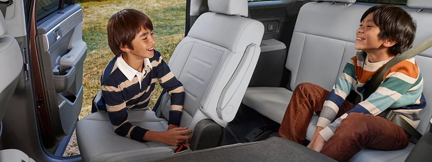 Two children seated in the second row of a SANTA FE with the door open