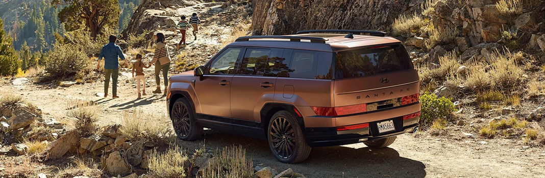 A copper SANTA FE parked on a ridge with a family walking nearby