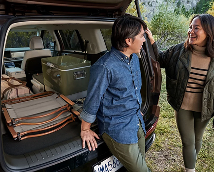 A couple at the open cargo area of a SANTA FE loaded for a trip