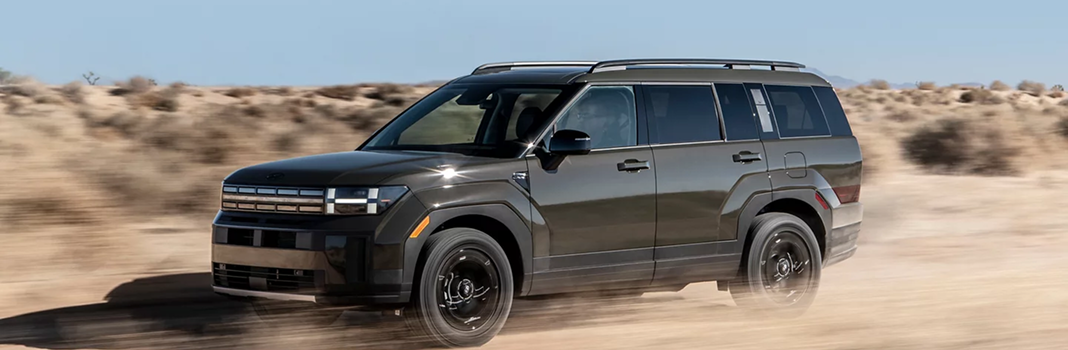 A dark olive SANTA FE driving through the desert