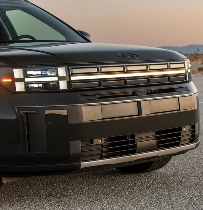 Close-up of the SANTA FE grille and H-shaped headlights at dusk