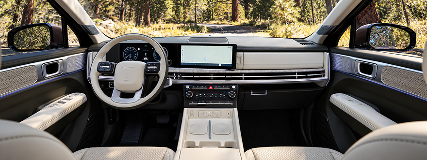 The SANTA FE Hybrid dashboard and light gray cabin with a forest view ahead
