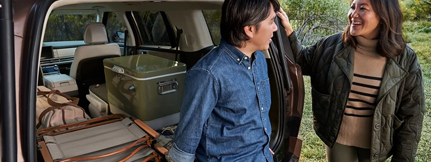 A couple at the open cargo area of a SANTA FE Hybrid outdoors