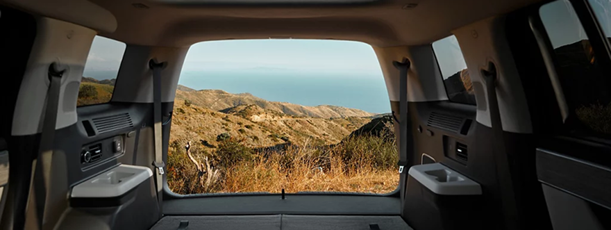 The SANTA FE Hybrid cargo area with the seats folded and a hillside view through the liftgate