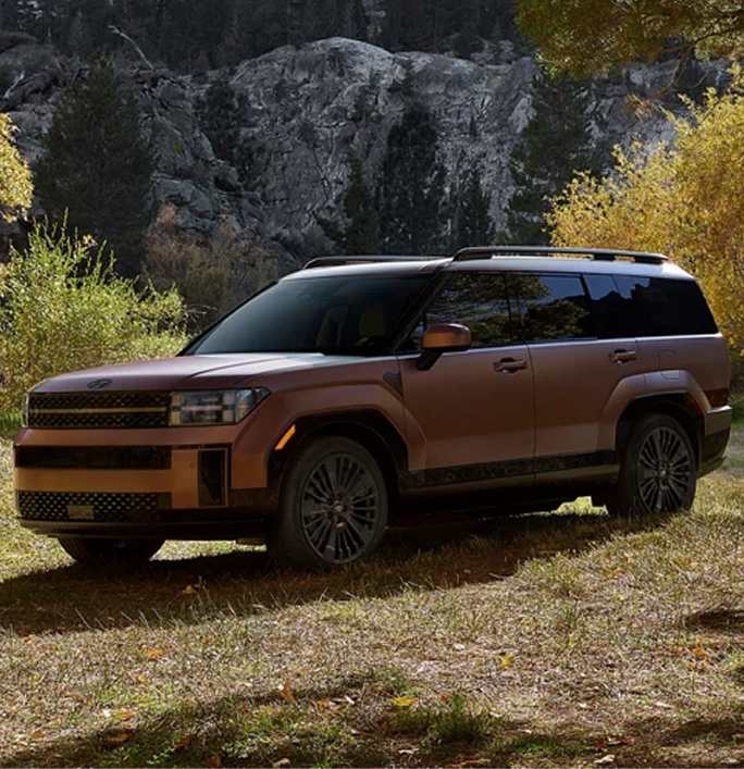 A copper SANTA FE Hybrid parked below a rocky bluff