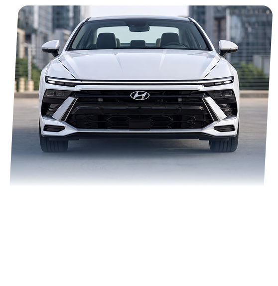 A white Hyundai sedan seen head-on on a city street
