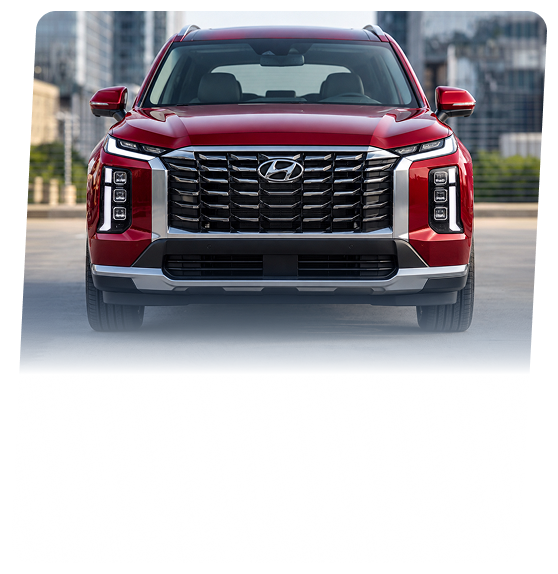 A red Hyundai Palisade SUV seen head-on on a city street