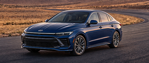 A dark blue Hyundai hybrid sedan on a desert road at sunset