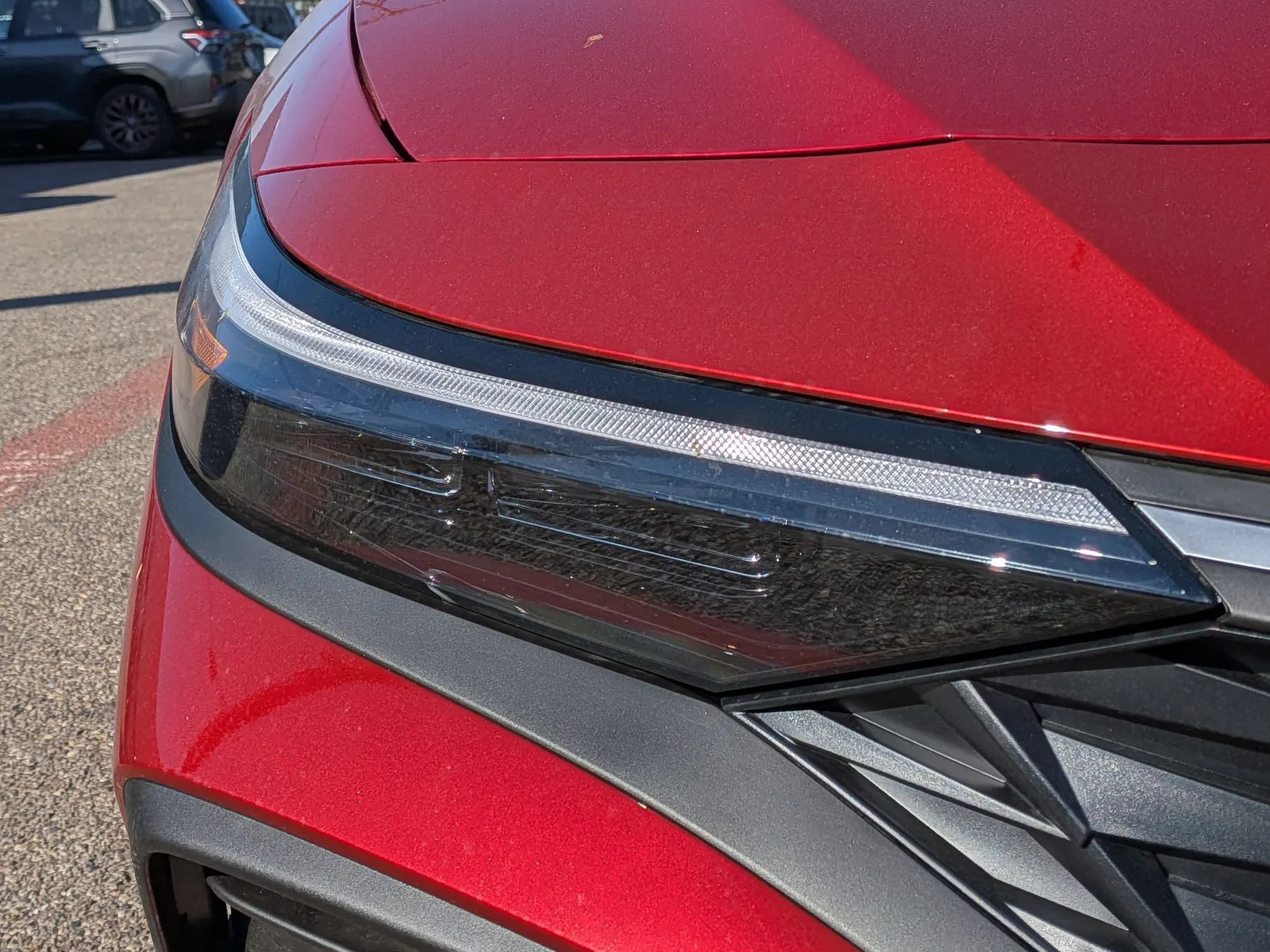 Close-up of the LED headlight and grille on a red 2026 Hyundai Elantra
