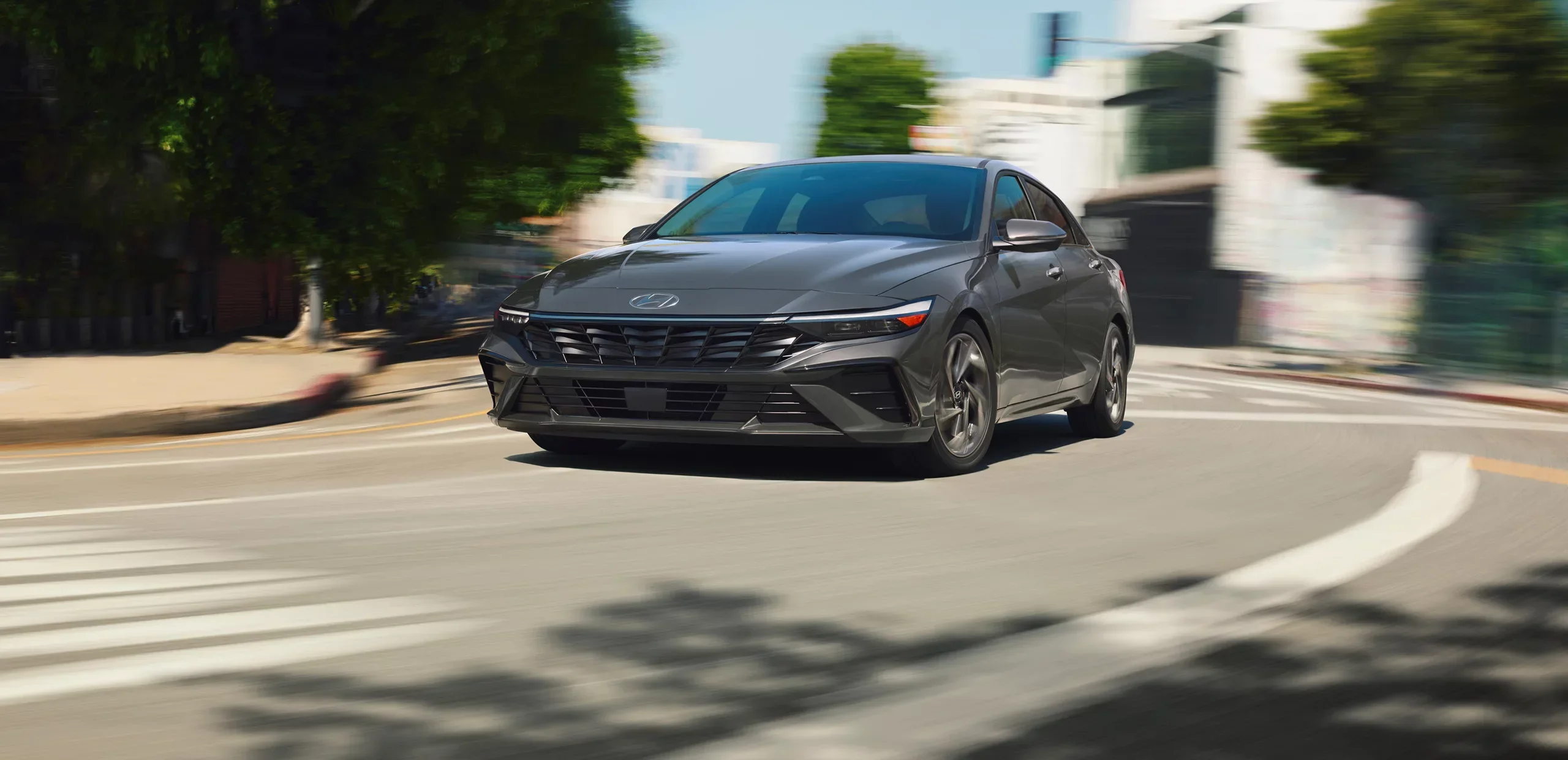 2026 Hyundai Elantra Hybrid driving on a city street, available to lease at Dalton Hyundai National City, CA