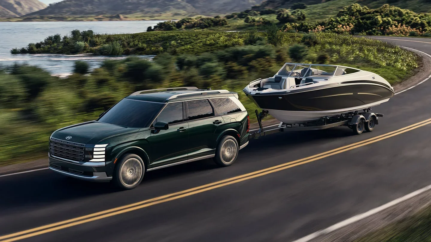 2026 Hyundai Palisade towing a boat on a lakeside road, available to lease at Dalton Hyundai National City, CA