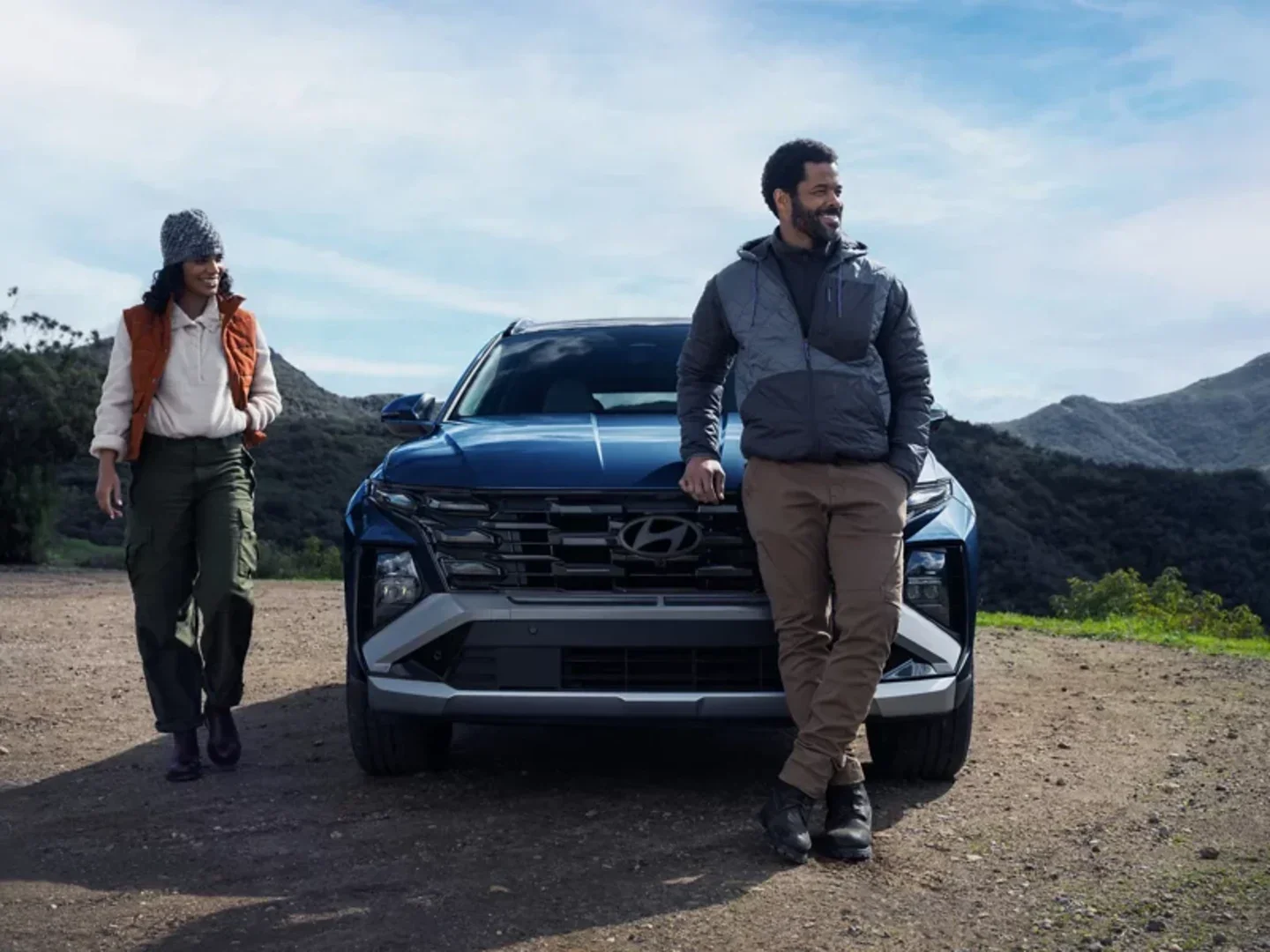 Couple standing beside a 2026 Hyundai Tucson at a mountain overlook, a compact SUV sold at Dalton Hyundai National City