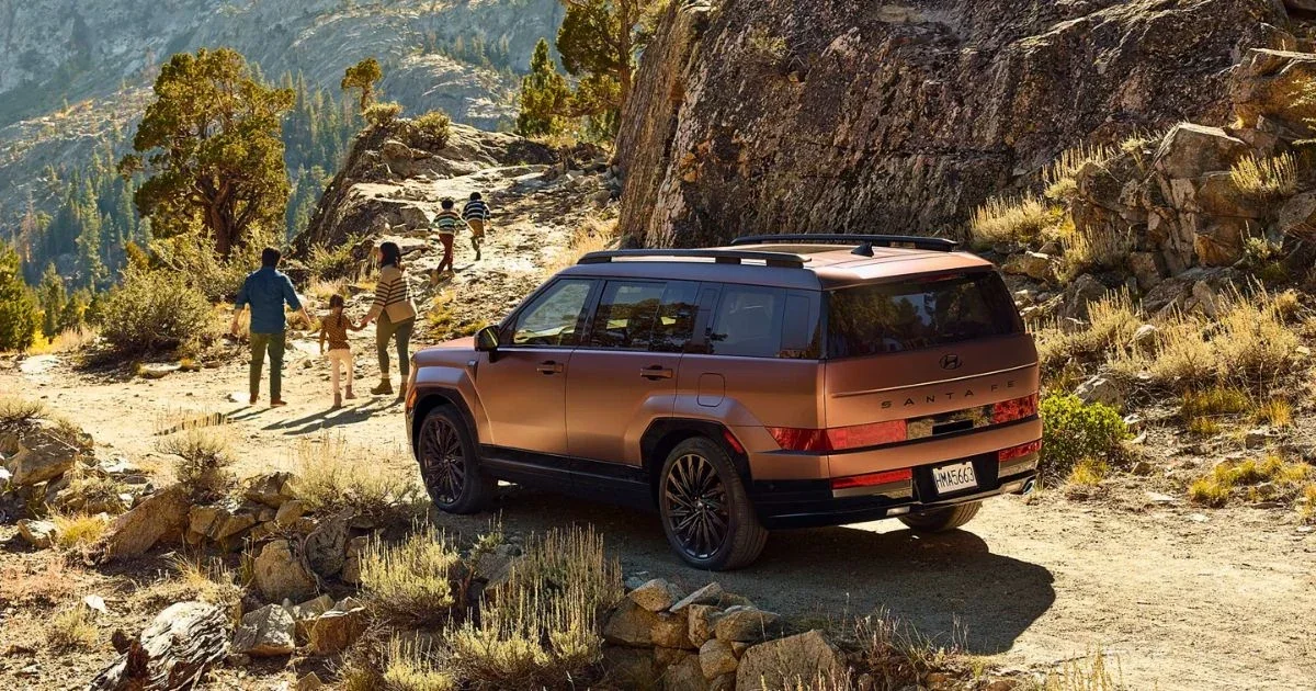 A Hyundai Santa Fe parked among rocks with a family hiking behind it.