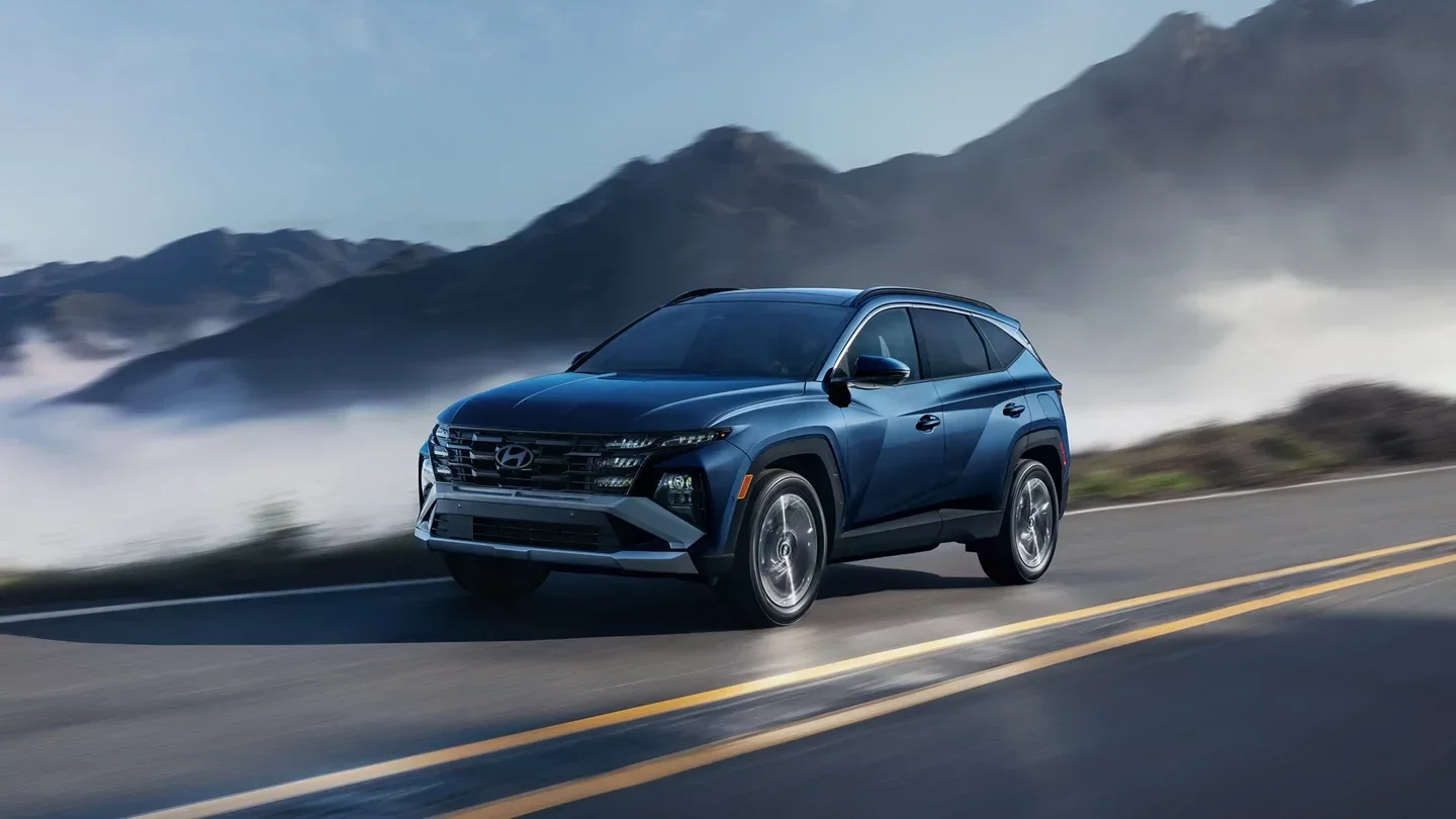 A blue Hyundai Tucson Hybrid on a mountain road above the fog.