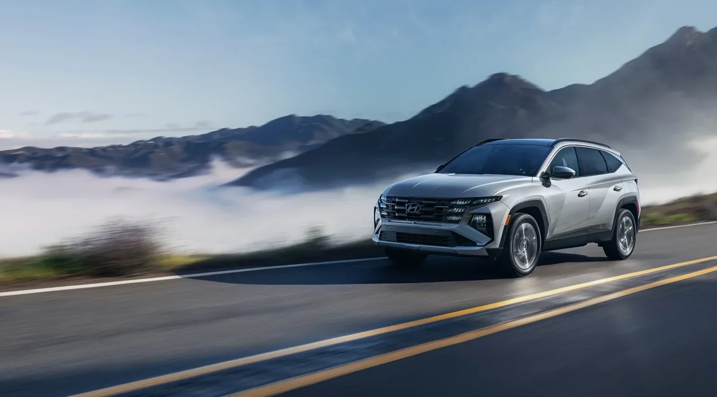 A silver Hyundai Tucson Plug-in Hybrid on a mountain road above the fog.