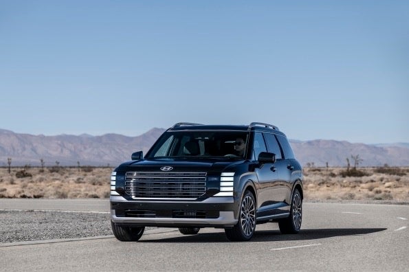 A dark blue Hyundai Palisade seen from the front and side on a desert road
