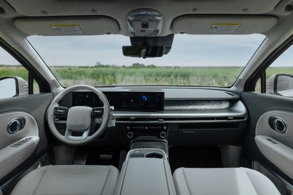 The IONIQ 9 dashboard viewed from the second row, with a curved display spanning the driver's cluster and the center screen