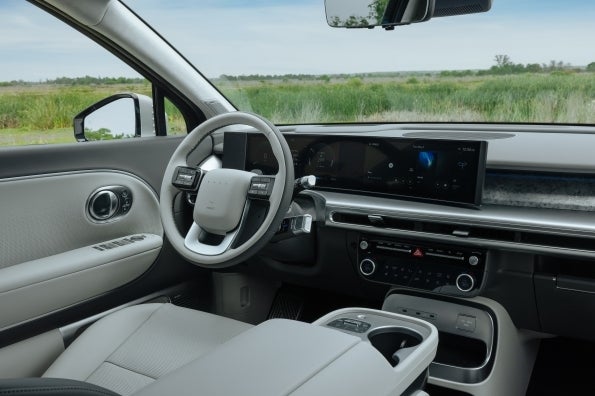 The IONIQ 9 driver's seat view, showing the steering wheel and the curved instrument and infotainment display