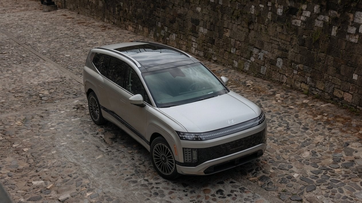 A Hyundai IONIQ 9 three-row electric SUV on a cobbled city street, seen from above