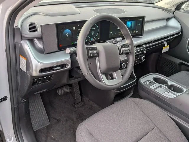 The IONIQ 9 driver's area seen from the passenger side, showing the steering wheel, dual displays and open center console